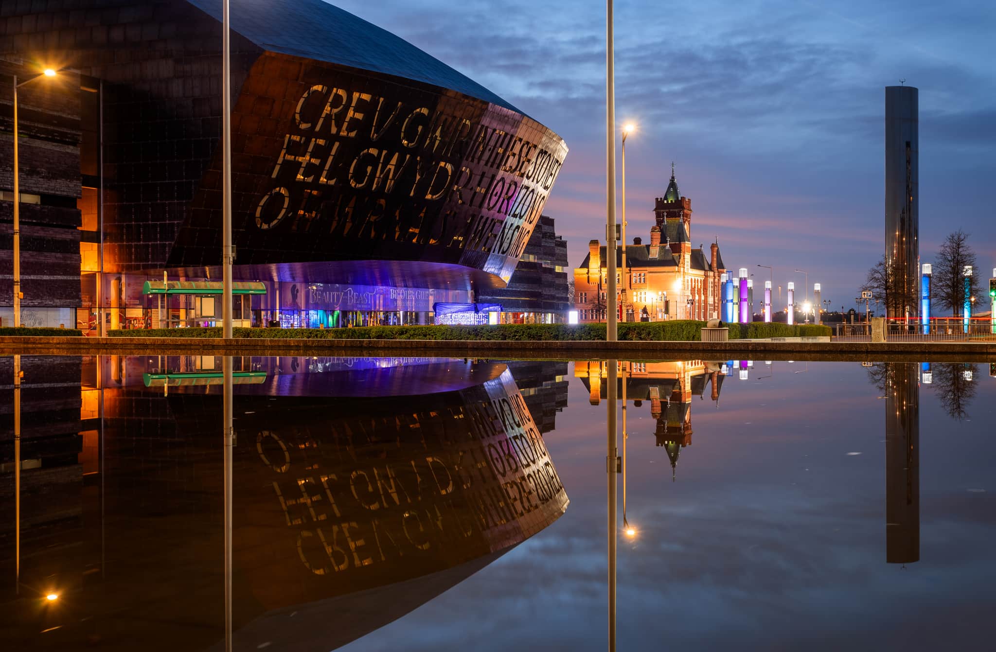 Cardiff's waterfront during the evening, with the Wales Millennium Centre reflected in the water.