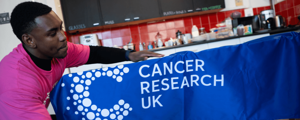 Man putting a CRUK branded table cover on.