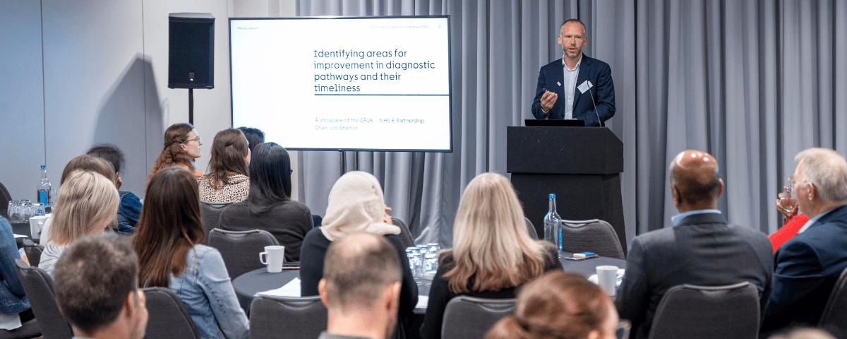 A presenter in front of an audience in a conference.