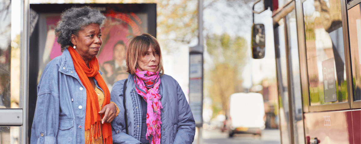 Two women are waiting at the bus stop about to board public transport.