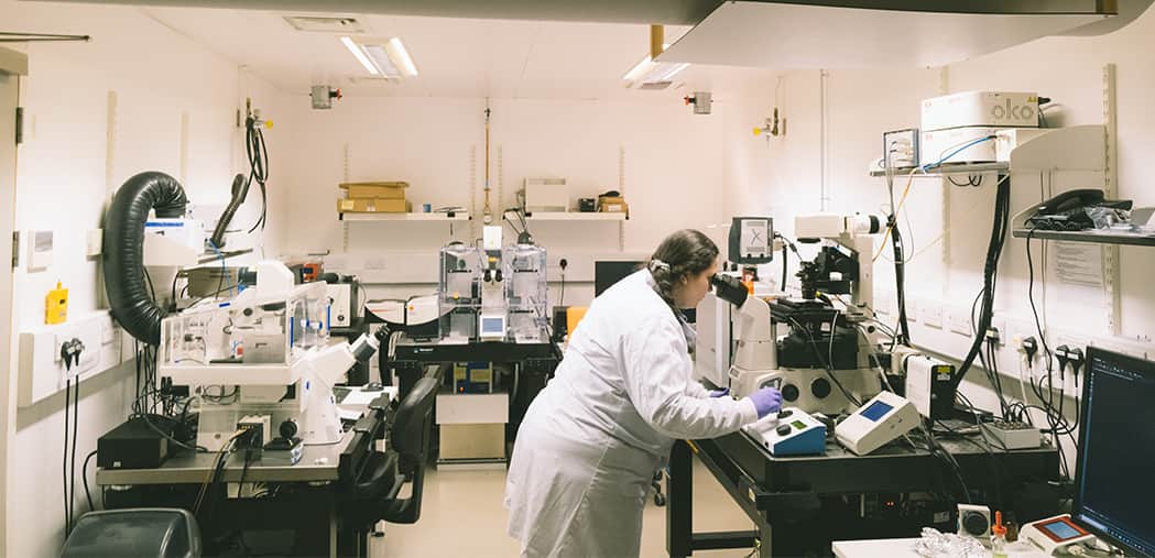 Researcher looking into a microscope. Moments captured at the Cambridge lab with our researchers working in the lab alone.