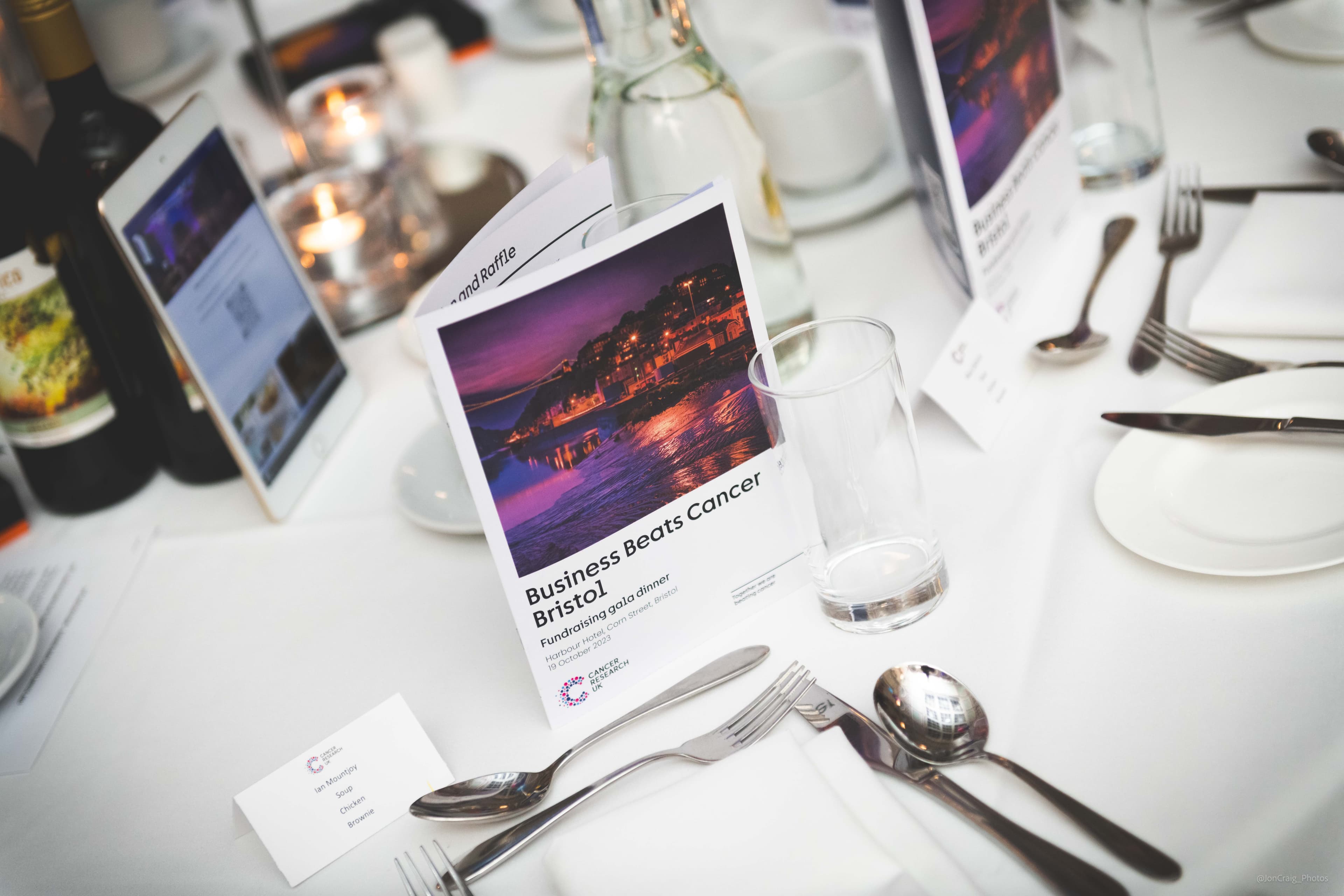 Image of table place setting at a Business Beats Cancer Bristol event with a printed program.