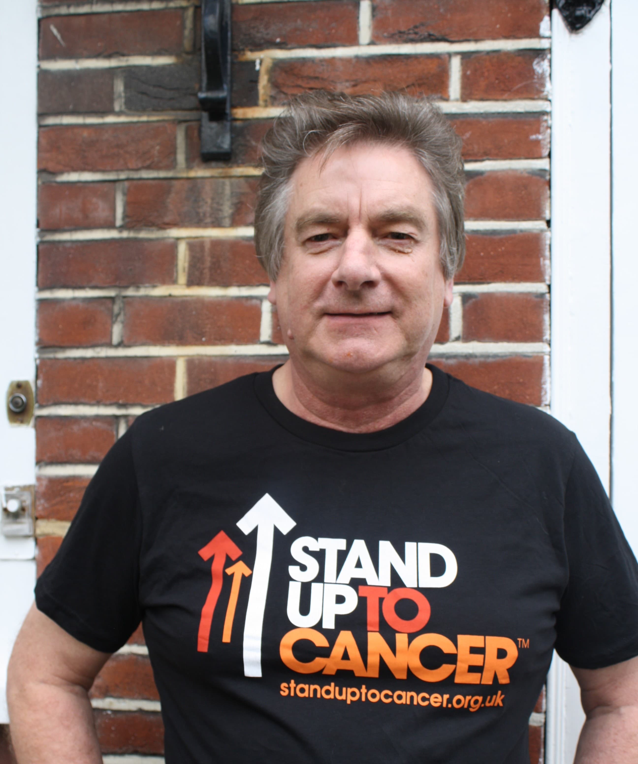 A picture of Keith smiling in a stand up to cancer t-shirt.