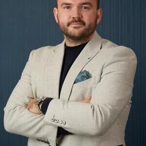 A man in a suit against a blue background.