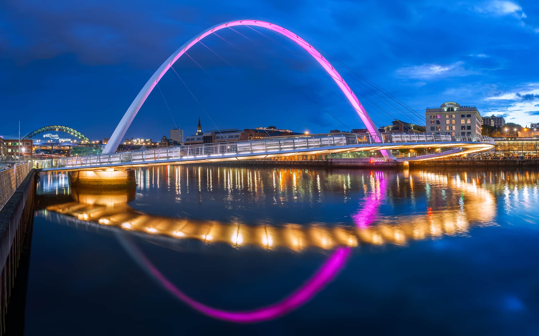 Newcaste at sundown with the Gateshead Millennium Bridge reflecting in the River Tyne.