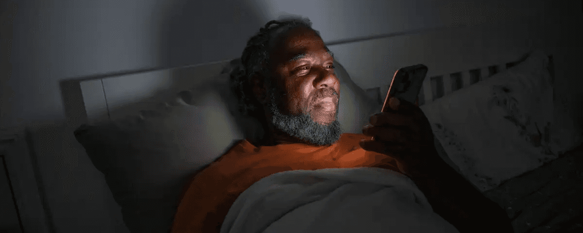 Image of a man reading his phone in bed.