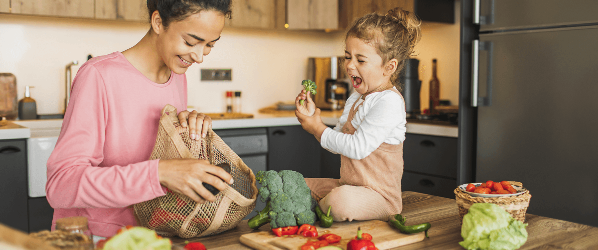 A photo of a mother and her toddler in a kitchen preparing food.