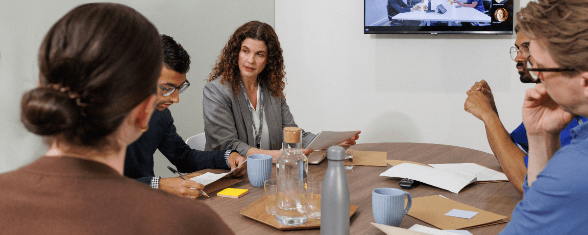 Group of healthcare professionals sat at a table reviewing patient files.