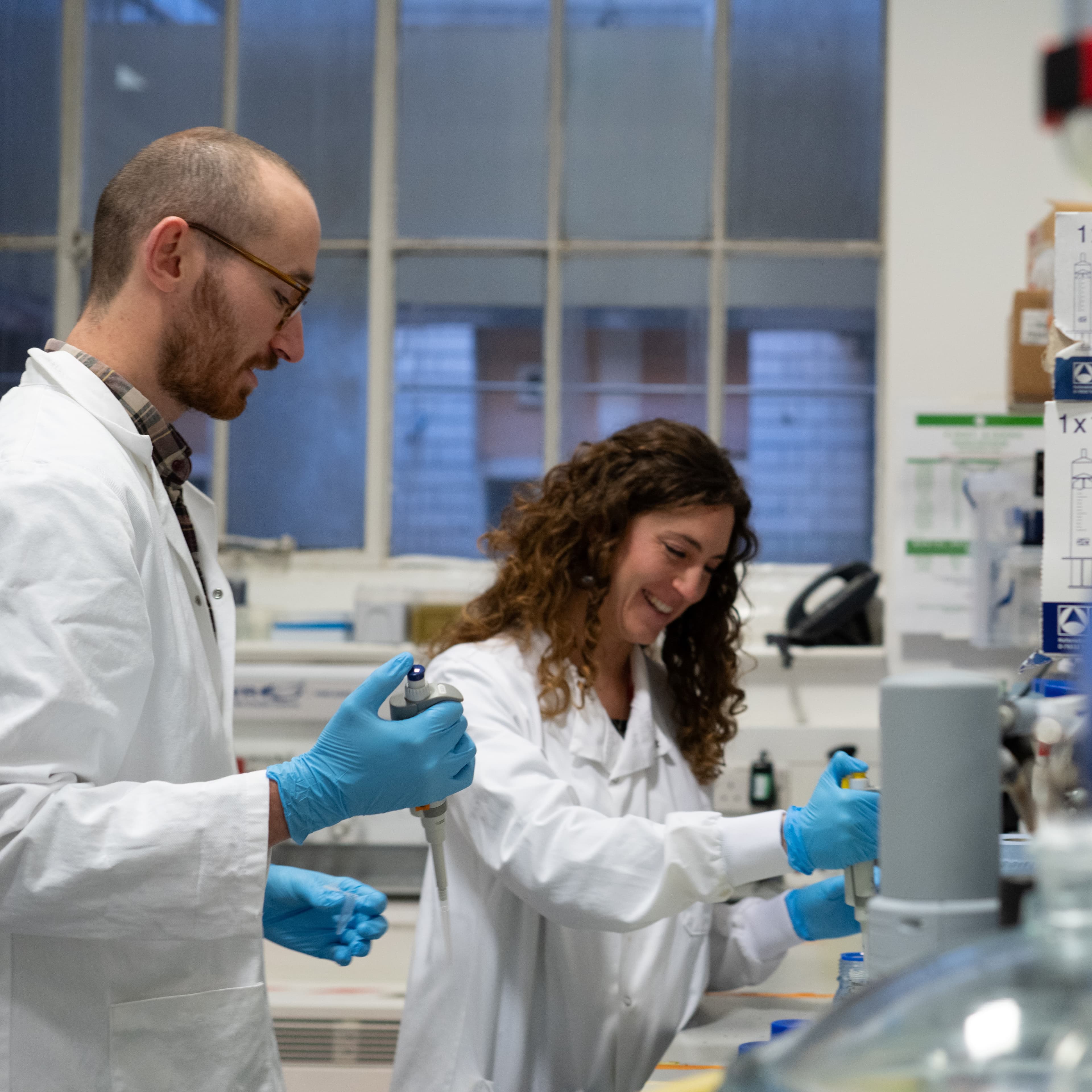 Image of researchers working together and pipetting samples in a lab.