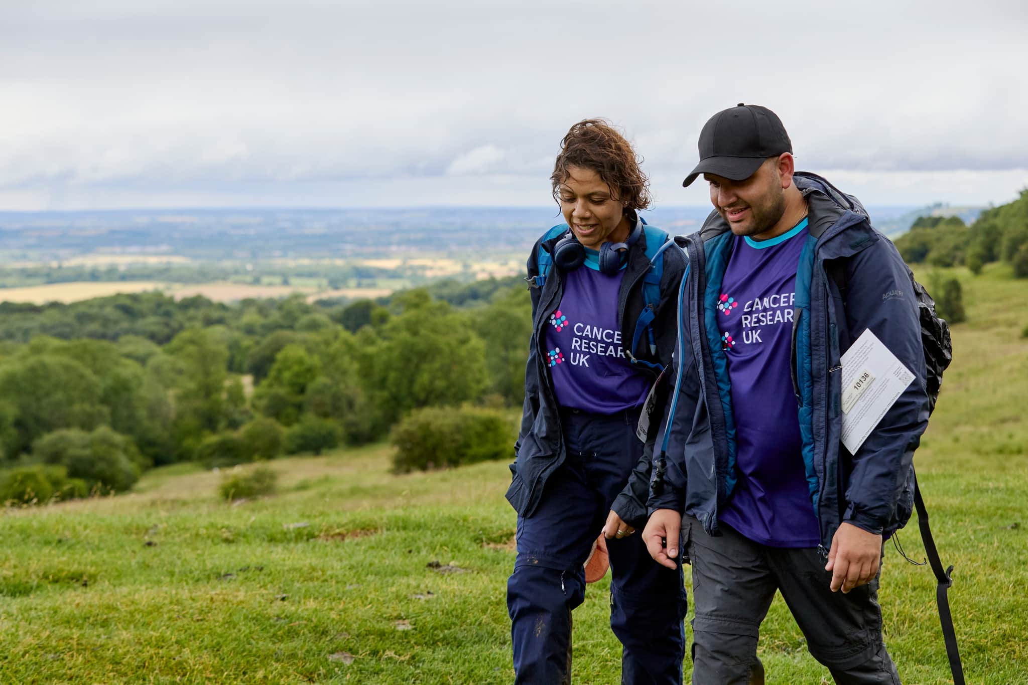 Two hikers chatting two each other, walking along the countryside path.