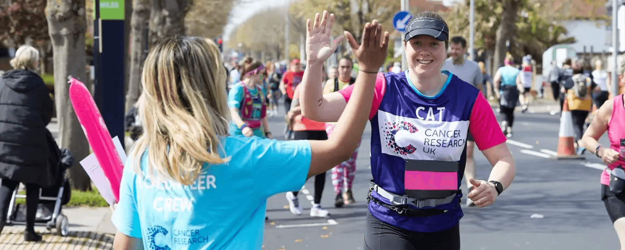 Supporter running in Brighton Marathon 2022 and going in for a high five with a member of the volunteer crew.