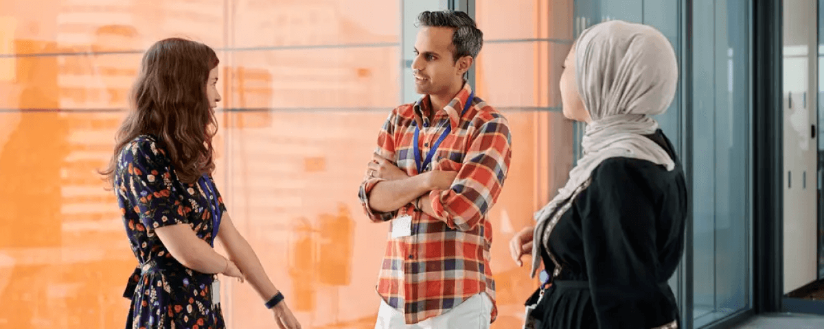 Three Cancer Research UK employees standing in an office, talking to each other.