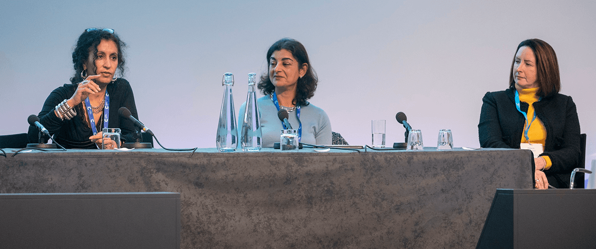 Three women sitting on a panel on stage.