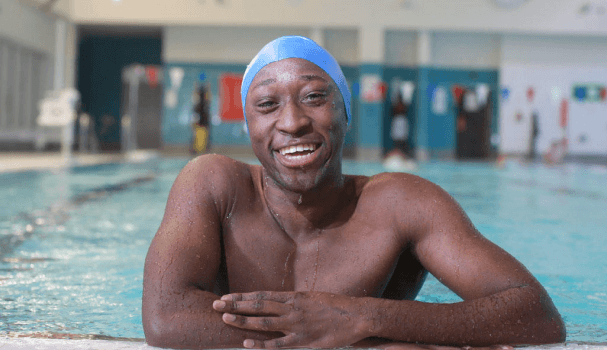 Male swimmer smiling by side of pool at swimathon.
