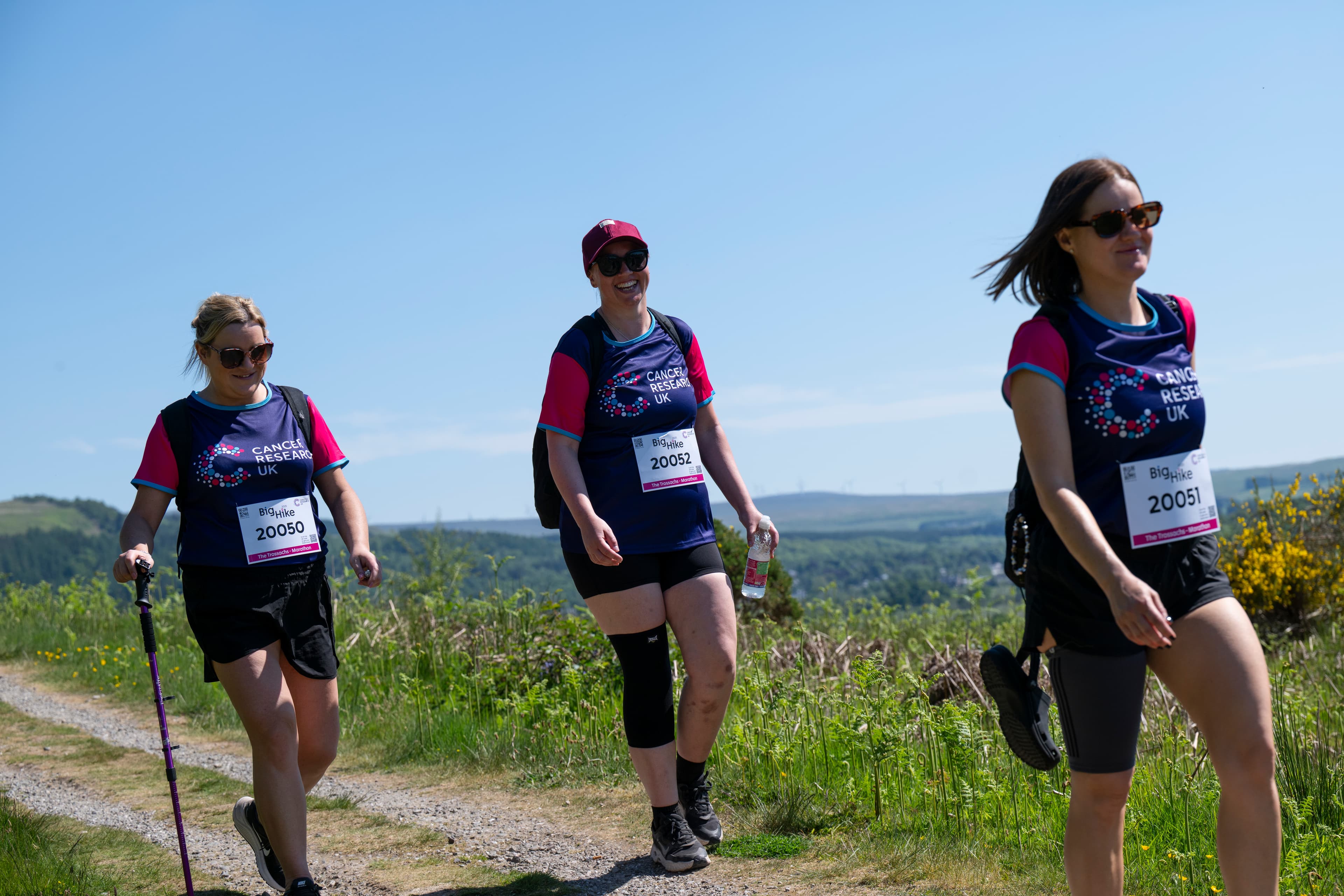 Three hikers walking along the countryside.